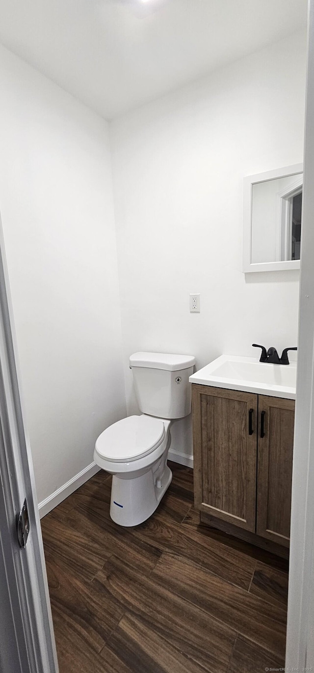 bathroom with toilet, vanity, and wood-type flooring