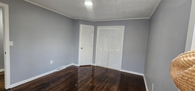 unfurnished bedroom featuring a closet, dark hardwood / wood-style flooring, and crown molding