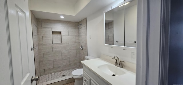 bathroom featuring toilet, vanity, and a tile shower