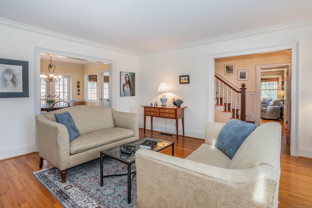 living room featuring a chandelier, ornamental molding, and light hardwood / wood-style flooring