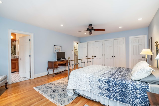 bedroom featuring connected bathroom, ceiling fan, hardwood / wood-style floors, and two closets