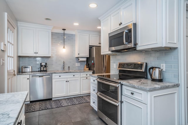 kitchen featuring sink, hanging light fixtures, light stone counters, white cabinets, and appliances with stainless steel finishes