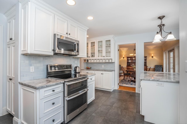 kitchen featuring white cabinets, decorative backsplash, pendant lighting, and stainless steel appliances