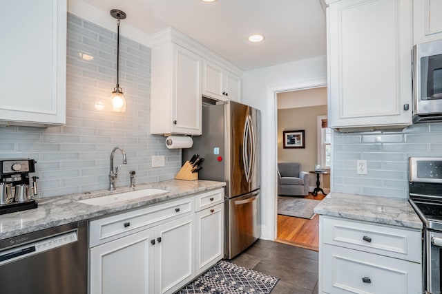 kitchen featuring hanging light fixtures, sink, light stone countertops, appliances with stainless steel finishes, and white cabinetry