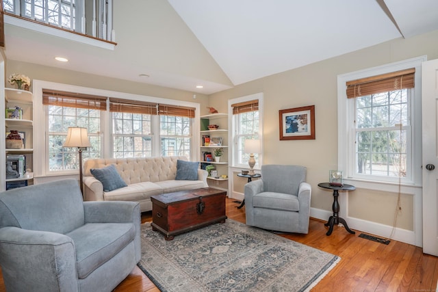 living room featuring a healthy amount of sunlight, light hardwood / wood-style floors, and high vaulted ceiling