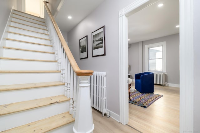 staircase with radiator heating unit and hardwood / wood-style floors