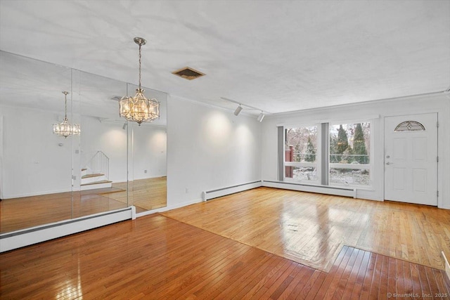 interior space with a baseboard radiator, track lighting, hardwood / wood-style flooring, and ornamental molding