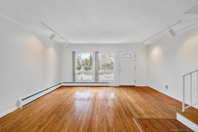 empty room with track lighting, crown molding, a baseboard heating unit, and light hardwood / wood-style flooring