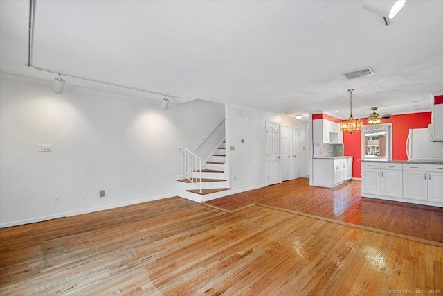 unfurnished living room with rail lighting, light hardwood / wood-style floors, and ceiling fan