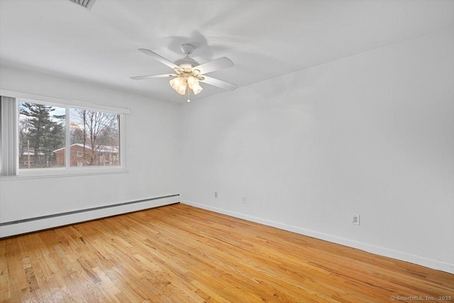 spare room featuring ceiling fan, a baseboard heating unit, and light hardwood / wood-style flooring