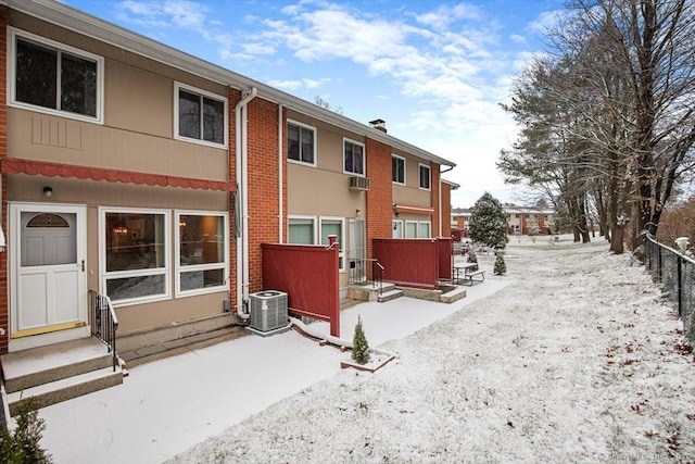 snow covered back of property featuring central air condition unit