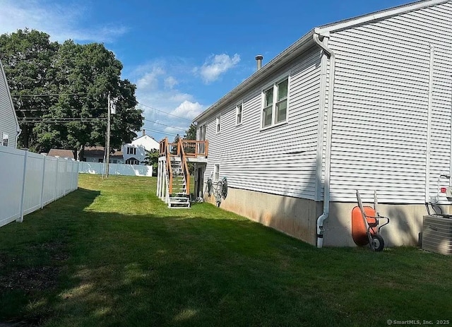 view of side of property featuring a lawn and central AC