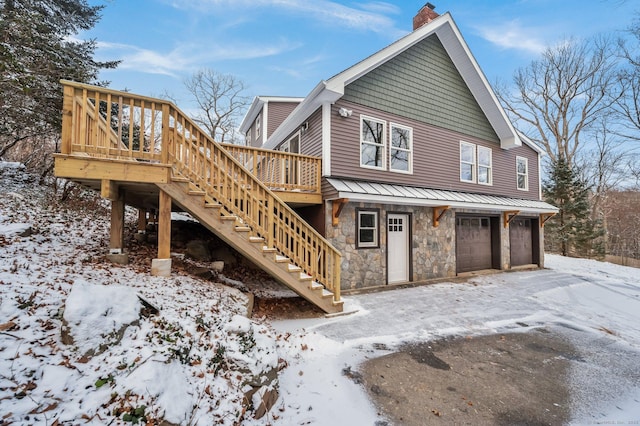 view of snow covered exterior featuring a garage and a deck