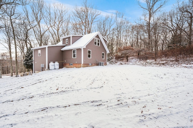 snow covered back of property featuring central AC