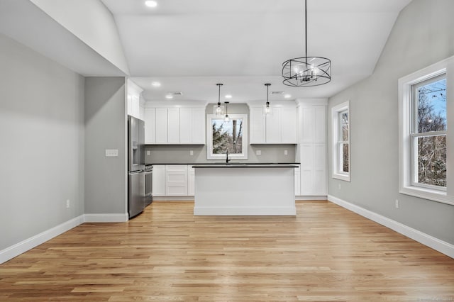 kitchen with light hardwood / wood-style floors, stainless steel refrigerator with ice dispenser, decorative light fixtures, vaulted ceiling, and white cabinets