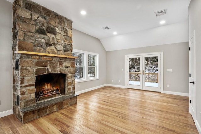 unfurnished living room with lofted ceiling, a fireplace, french doors, and light hardwood / wood-style floors