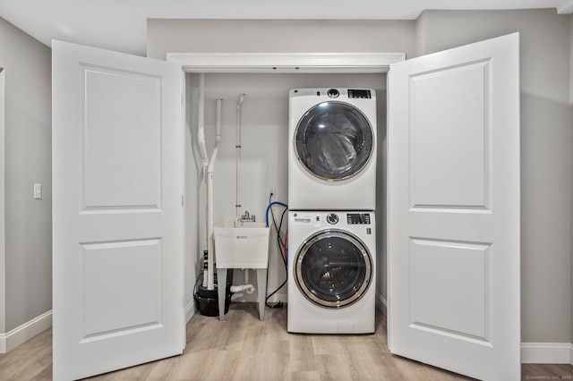 clothes washing area with light hardwood / wood-style floors and stacked washer and clothes dryer