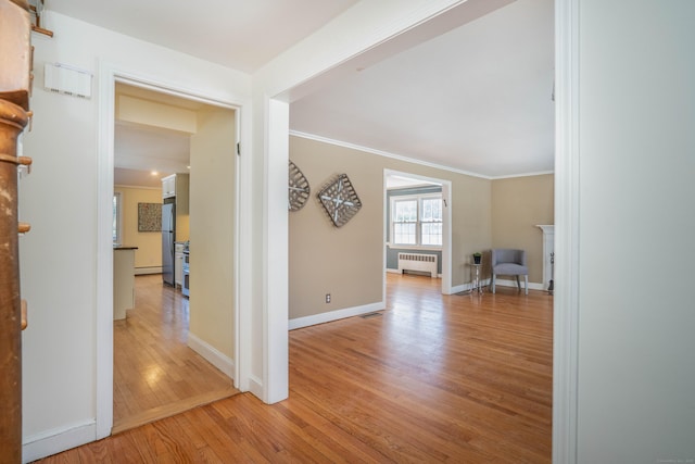 hallway featuring light hardwood / wood-style flooring, radiator heating unit, and ornamental molding