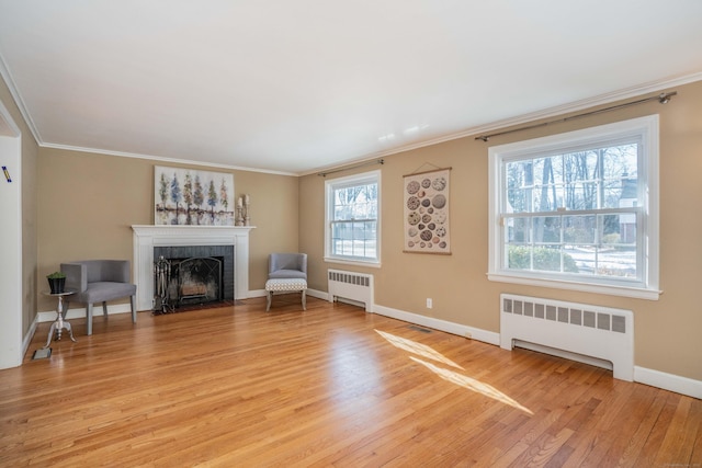 sitting room with crown molding, radiator heating unit, and a healthy amount of sunlight