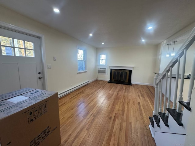 foyer featuring hardwood / wood-style floors, a wall unit AC, and a baseboard heating unit