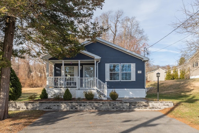 bungalow-style home with covered porch and a front yard