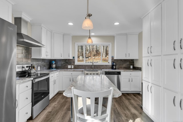 kitchen with white cabinetry, stainless steel appliances, tasteful backsplash, hanging light fixtures, and wall chimney exhaust hood