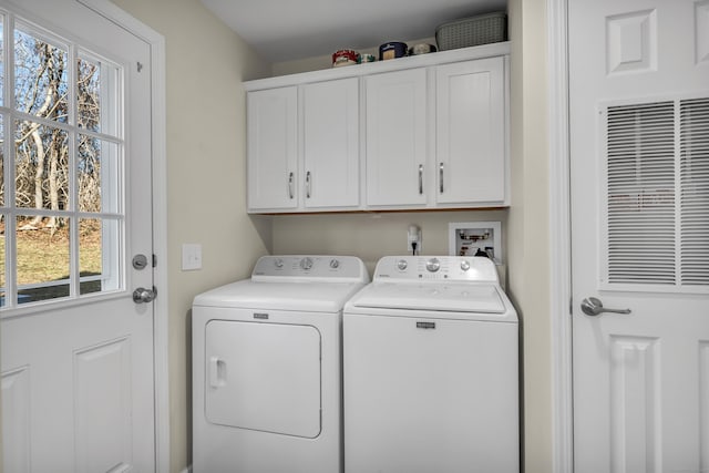 laundry room with washer and clothes dryer, a healthy amount of sunlight, and cabinets