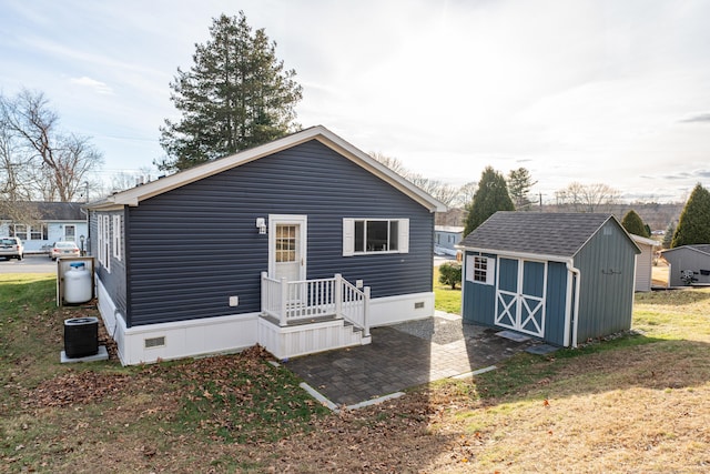 rear view of house featuring central AC, a shed, and a yard