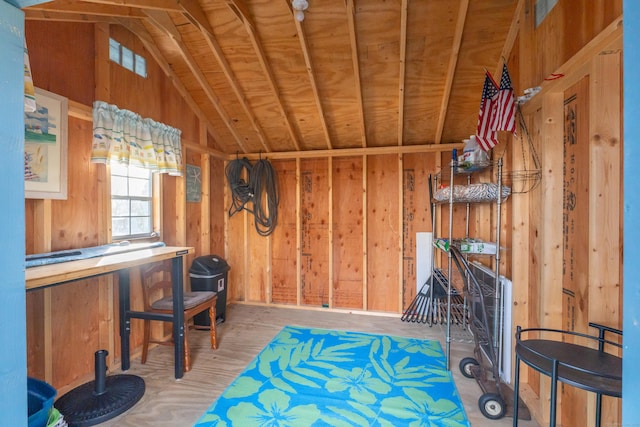 miscellaneous room featuring lofted ceiling and wooden walls