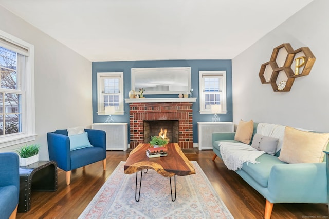 living room featuring a brick fireplace, radiator, and dark wood-type flooring