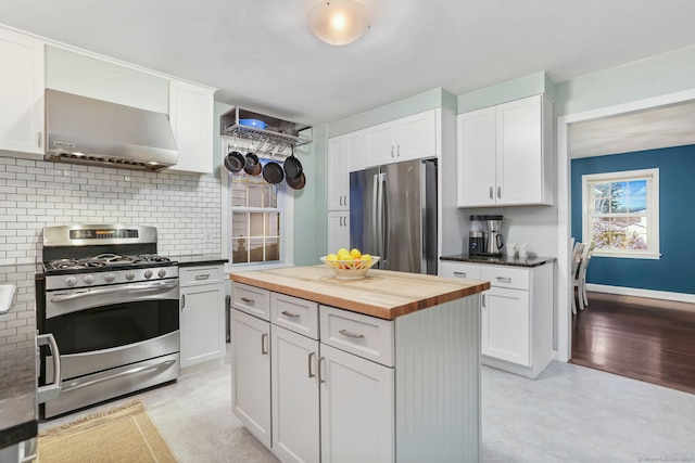 kitchen with wooden counters, white cabinets, wall chimney range hood, a kitchen island, and stainless steel appliances