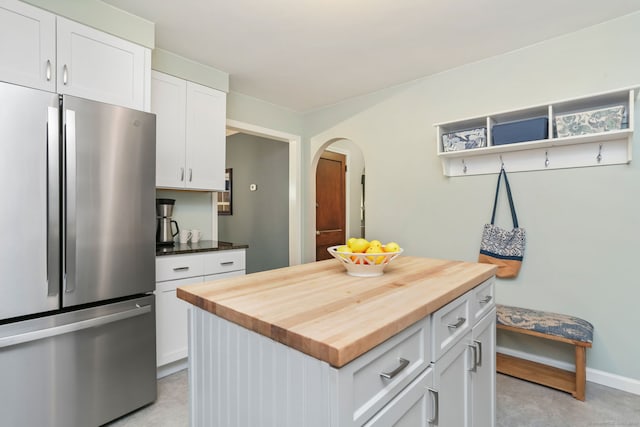 kitchen featuring butcher block countertops, stainless steel refrigerator, white cabinetry, and a kitchen island