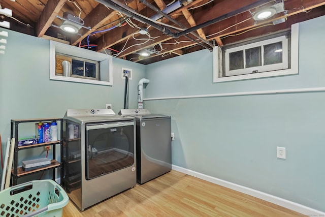 clothes washing area with hardwood / wood-style floors and washer and dryer