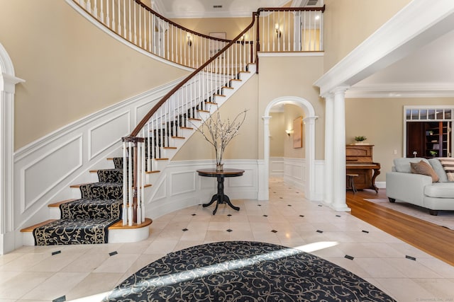 entrance foyer featuring tile patterned flooring, crown molding, and ornate columns