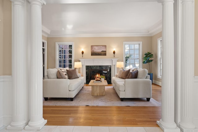 living room with ornate columns, ornamental molding, and a fireplace