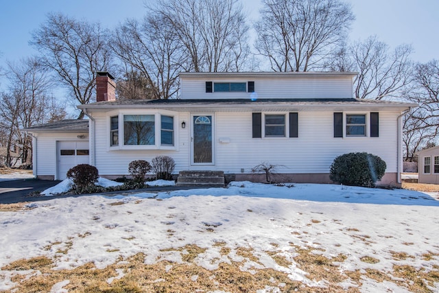 view of front of house with aphalt driveway, a chimney, and an attached garage