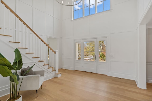 entrance foyer featuring a towering ceiling and light wood-type flooring