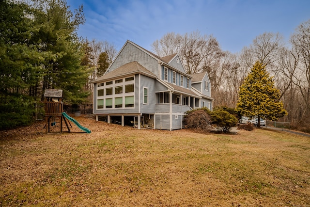 back of house featuring a playground and a yard