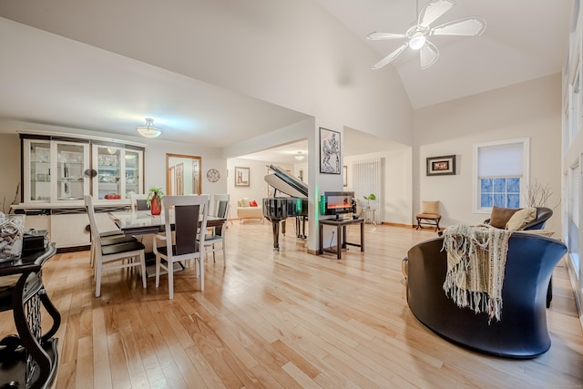 dining room with hardwood / wood-style floors, high vaulted ceiling, and ceiling fan