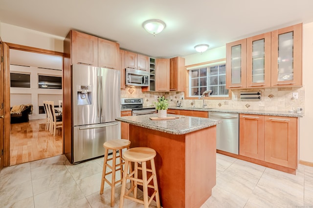 kitchen featuring sink, a kitchen island, light stone countertops, and stainless steel appliances