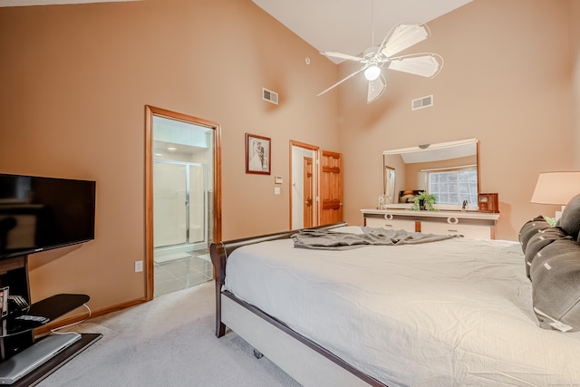 bedroom with ceiling fan, ensuite bath, light colored carpet, and a towering ceiling