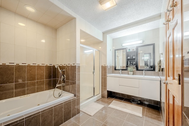 bathroom with a textured ceiling, tile walls, vanity, and tile patterned floors