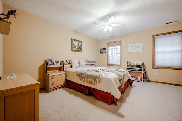 carpeted bedroom with ceiling fan and a textured ceiling