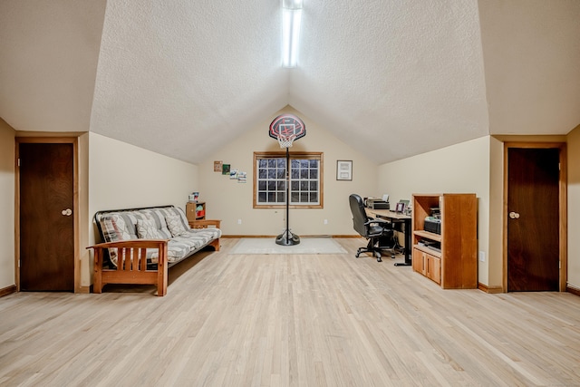 home office featuring light hardwood / wood-style flooring, vaulted ceiling, and a textured ceiling