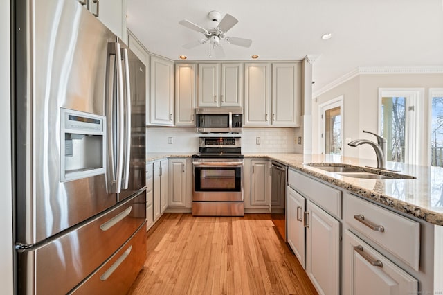 kitchen featuring stainless steel appliances, light hardwood / wood-style floors, sink, backsplash, and light stone counters