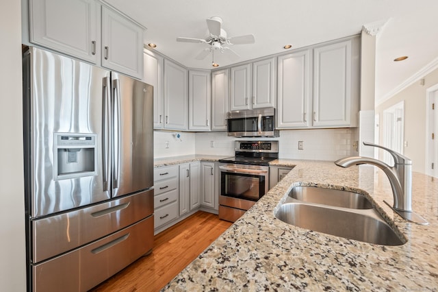 kitchen featuring ceiling fan, sink, light stone counters, and stainless steel appliances