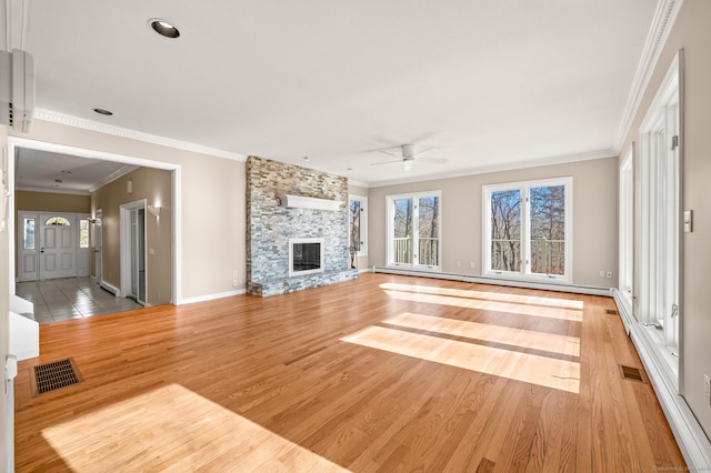 unfurnished living room with crown molding, a wealth of natural light, a stone fireplace, and light hardwood / wood-style flooring