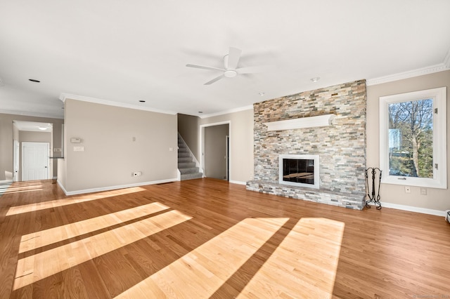 unfurnished living room with hardwood / wood-style flooring, ceiling fan, ornamental molding, and a stone fireplace