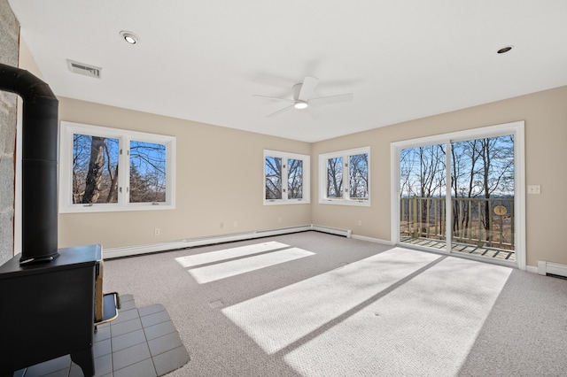 carpeted living room with ceiling fan, a wood stove, and a baseboard heating unit