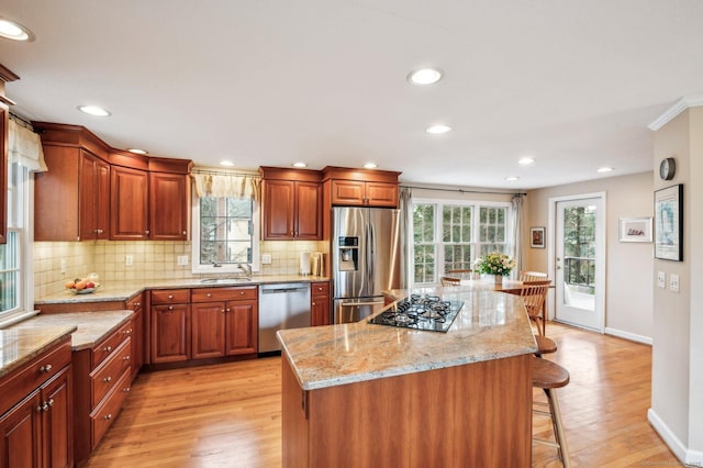 kitchen with a breakfast bar, a center island, light stone countertops, light hardwood / wood-style floors, and stainless steel appliances